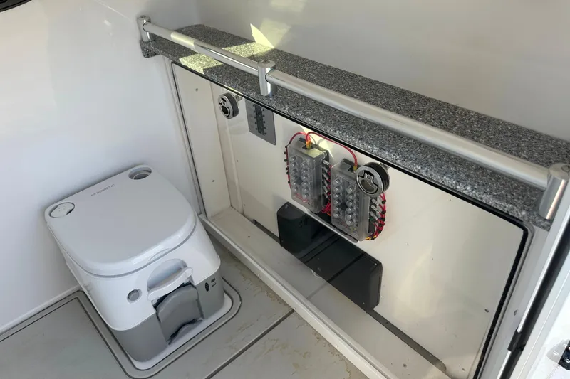 Slide: The Image of 2026 Twin Vee 260 GFX2 CC boat interior with portable toilet and electrical panel. - 25