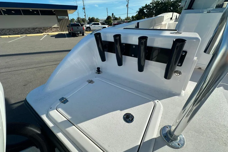 Slide: The Image of 2026 Twin Vee 260 GFX2 CC boat deck with rod holders in a parking lot. - 5