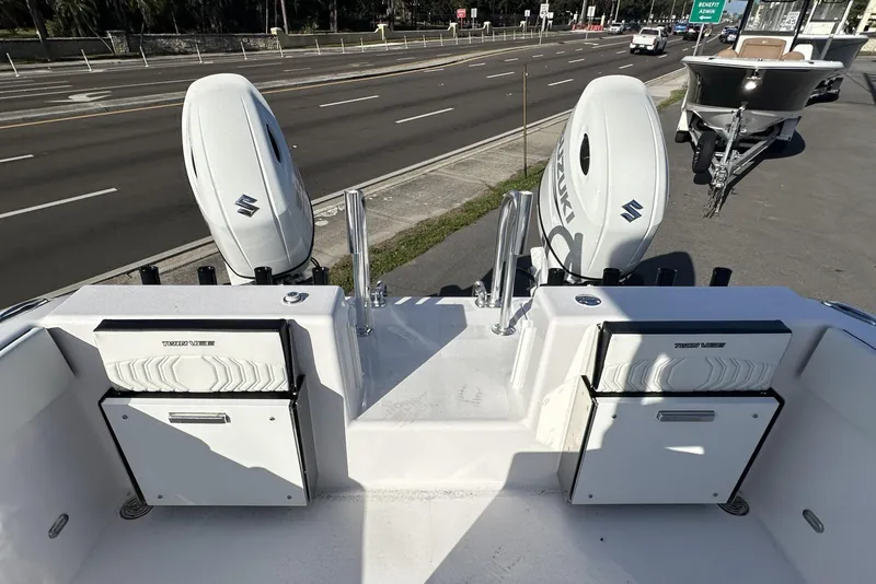 Slide: The Image of 2026 Twin Vee 260 GFX2 CC boat with dual Suzuki outboard motors on a roadside. - 8