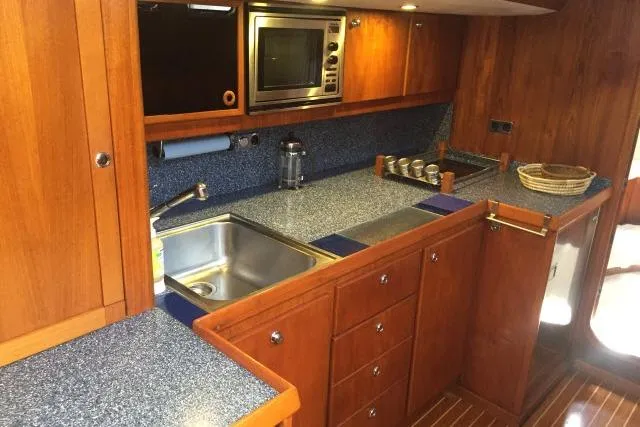 Slide: The Image of Kitchen area of a 1997 Gorbon Custom 66 yacht with wooden cabinetry and modern appliances. - 140