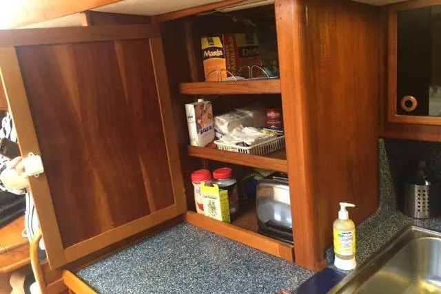 Slide: The Image of Wooden kitchen cabinet with open shelves, displaying various food items and a countertop in a Gorbon Custom 66 yacht. - 142