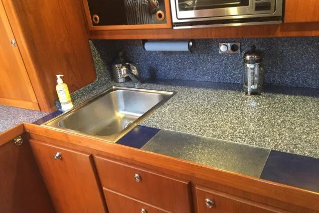 Slide: The Image of Kitchen area of a 1997 Gorbon Custom 66 yacht with wooden cabinets and stainless steel sink. - 144