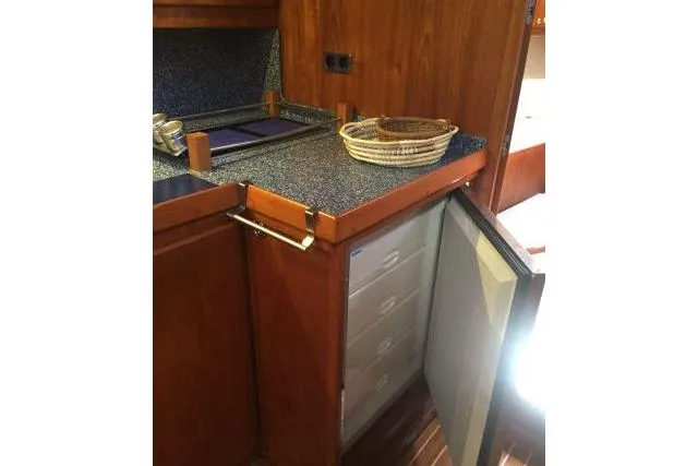 Slide: The Image of Kitchen area of 1997 Gorbon Custom 66 yacht with open fridge and wooden cabinetry. - 148