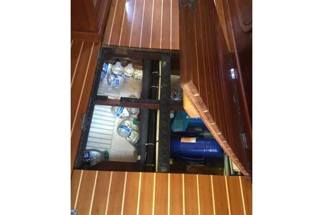 Slide: The Image of Wooden floor compartment on a 1997 Gorbon Custom 66 yacht, storing water bottles and supplies. - 151