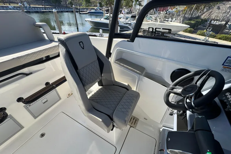 Slide: The Image of Modern Navan S30 boat interior with sleek steering and quilted seating, docked by the water. - 14