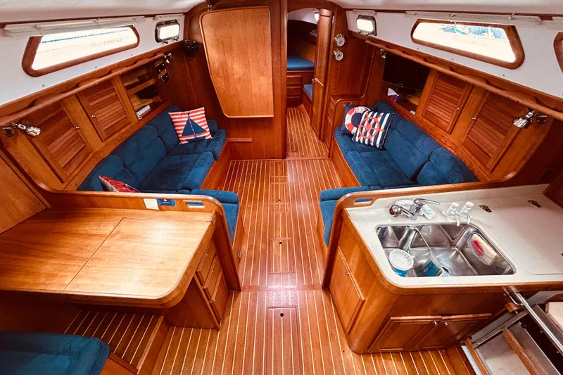 Slide: The Image of Interior of 2004 Sabre 426 yacht with wooden finish, blue sofas, and compact kitchen area. - 22