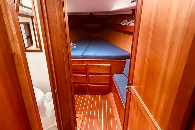 Slide: The Image of 2004 Sabre 426 yacht interior with wooden cabinetry, blue cushions, and compact bathroom. - 30