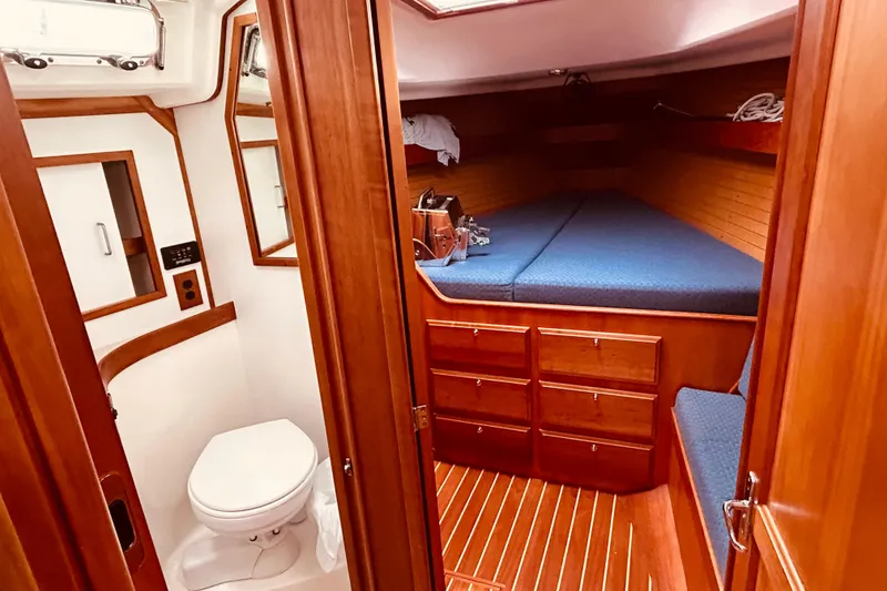Slide: The Image of 2004 Sabre 426 yacht interior with wooden cabinetry, cozy bed, and compact bathroom. - 31