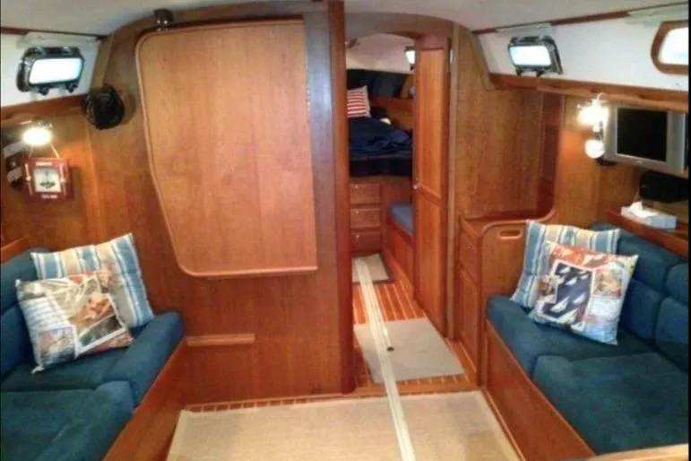 Slide: The Image of 2004 Sabre 426 yacht interior with wooden finish, blue seating, and cozy cabin layout. - 4