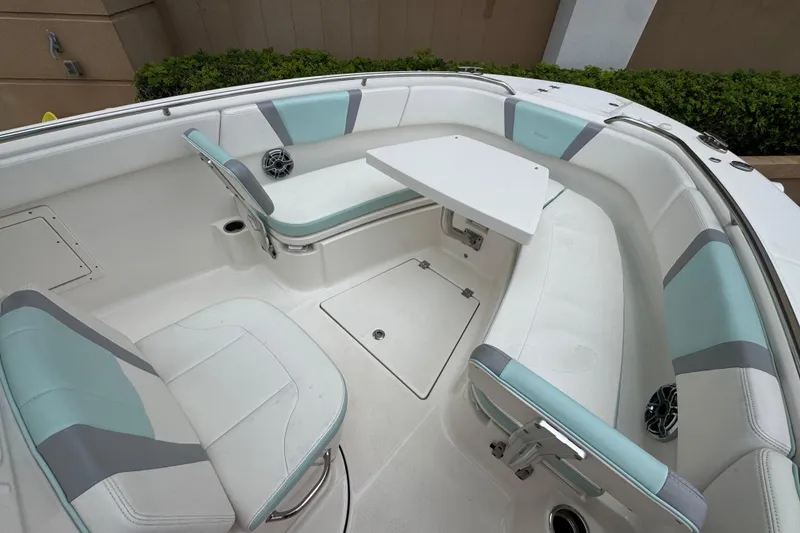 Slide: The Image of 2023 Robalo R272 Center Console boat interior with cushioned seating and table. - 11