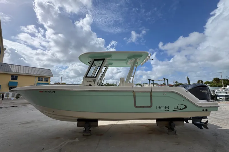 Slide: The Image of 2023 Robalo R272 Center Console boat on display under a partly cloudy sky. - 2