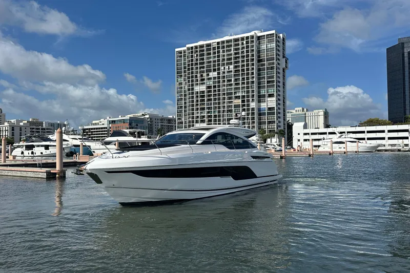 Slide: The Image of 2026 Fairline Targa 47 GT yacht docked in a marina with cityscape background. - 2
