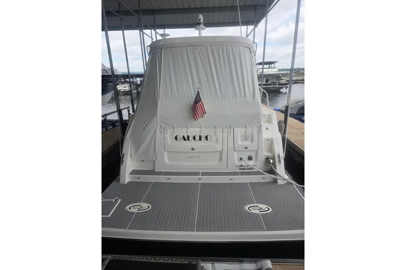 Slide: The Image of 2021 Regal 38 Grande Coupe yacht docked, rear view with covered deck and American flag. - 1
