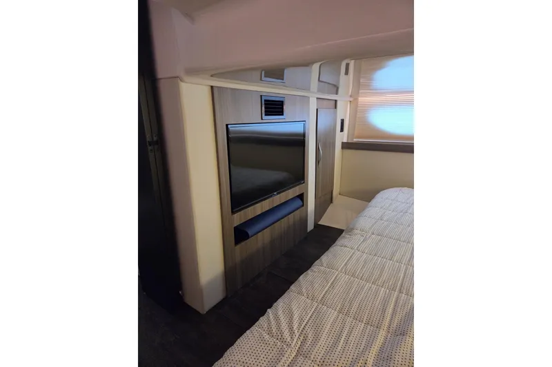 Slide: The Image of Interior of 2021 Regal 38 Grande Coupe featuring a mounted TV and cozy bedding. - 14