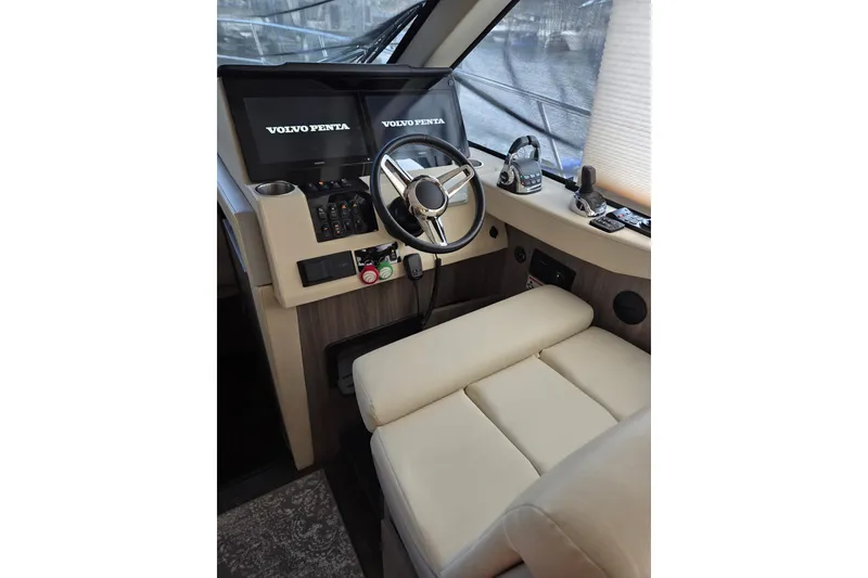 Slide: The Image of 2021 Regal 38 Grande Coupe helm with Volvo Penta controls and beige seating. - 7