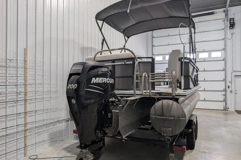 Slide: The Image of 2018 Lund LX220 Pontoon with Mercury 200 engine in a garage setting. - 2