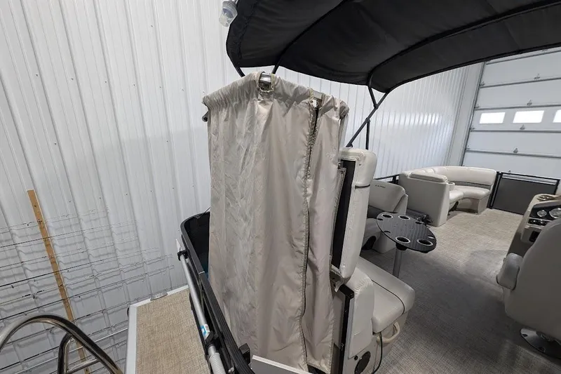 Slide: The Image of 2018 Lund LX220 Pontoon interior with seating and privacy curtain in a garage setting. - 24
