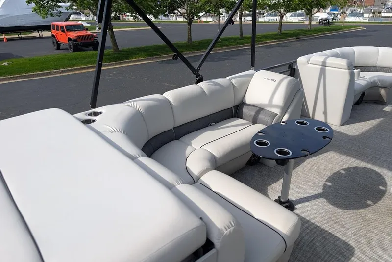 Slide: The Image of 2018 Lund LX220 Pontoon boat with plush seating and cupholder table on deck. - 37
