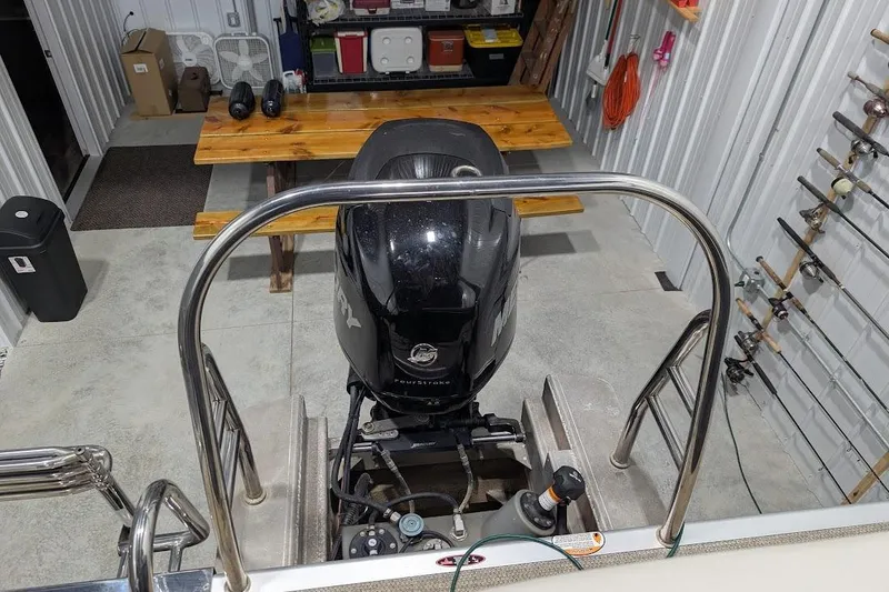 Slide: The Image of 2018 Lund LX220 Pontoon boat engine in a garage with fishing rods. - 42