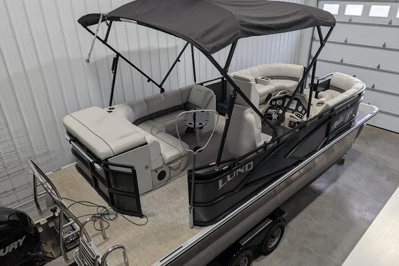 Slide: The Image of 2018 Lund LX220 Pontoon boat with canopy in a garage setting. - 7