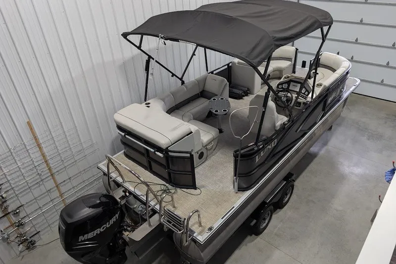 Slide: The Image of 2018 Lund LX220 Pontoon boat in a garage, featuring a Mercury outboard motor. - 8