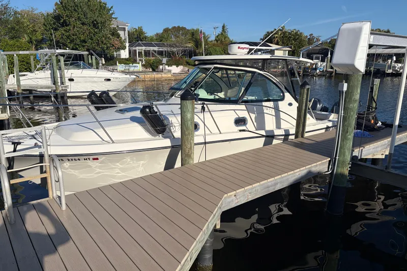 The Image of 2005 Pursuit 3370 Offshore boat docked at a marina under clear skies. - 1