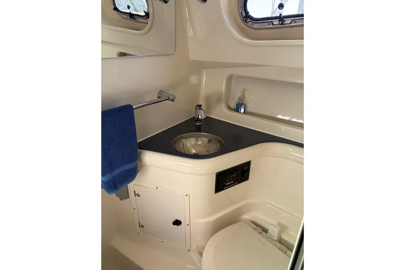 Slide: The Image of 2005 Pursuit 3370 Offshore boat bathroom with sink, toilet, and blue towel. - 25