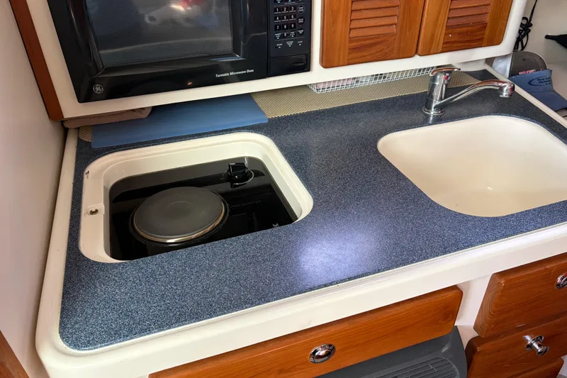 Slide: The Image of 2005 Pursuit 3370 Offshore boat kitchen with stove, sink, and microwave. - 27