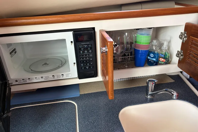 Slide: The Image of 2005 Pursuit 3370 Offshore kitchen with microwave, sink, and storage cabinet. - 28