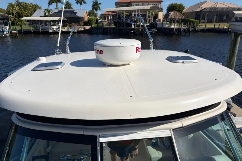 Slide: The Image of 2005 Pursuit 3370 Offshore boat with radar dome, docked near waterfront homes. - 32