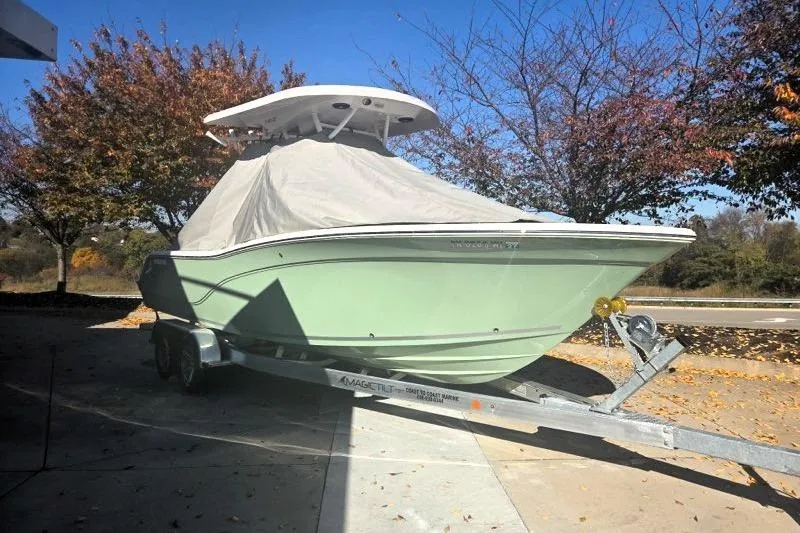 Slide: The Image of 2024 Seafox 248 Side Console boat on trailer, covered, with autumn trees in the background. - 3