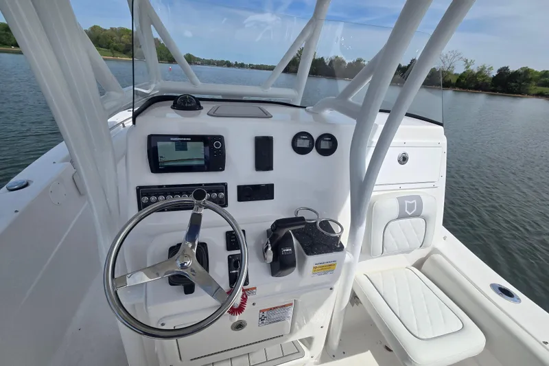 Slide: The Image of 2024 Sea Fox 248 Side Console boat with white cushioned seating on a calm lake. - 9