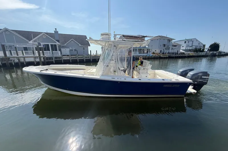 Slide: The Image of 2009 Regulator 26 Forward Seating boat on calm water near waterfront homes. - 2