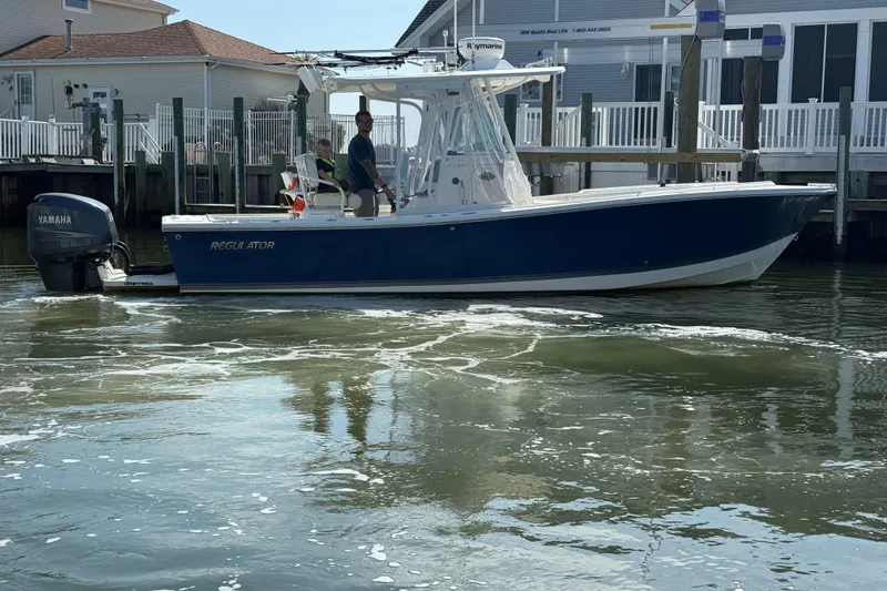 Slide: The Image of 2009 Regulator 26 Forward Seating boat with Yamaha engine on calm water near docks. - 6