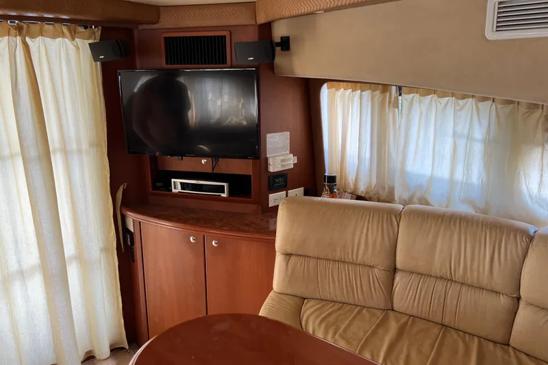 Slide: The Image of Interior of 2006 Silverton 38 Sport Bridge with TV, beige sofa, and wooden cabinetry. - 13