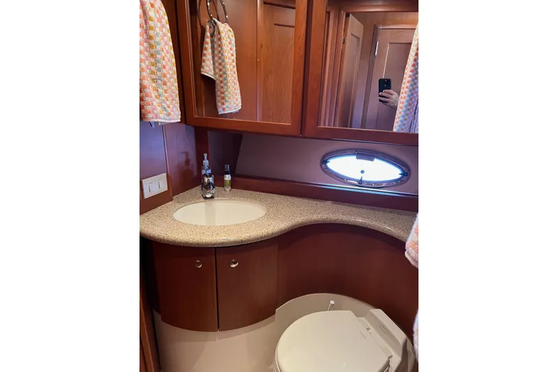 Slide: The Image of 2006 Silverton 38 Sport Bridge bathroom with wooden cabinetry and oval window. - 15