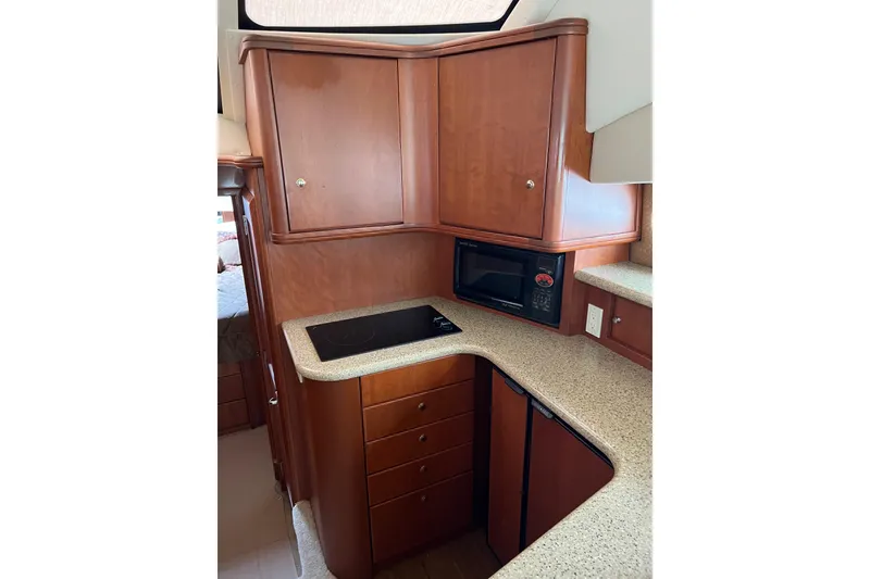 Slide: The Image of 2006 Silverton 38 Sport Bridge kitchen with wooden cabinets, microwave, and stovetop. - 19