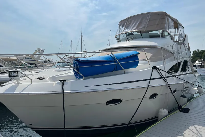 Slide: The Image of 2006 Silverton 38 Sport Bridge yacht docked at marina, featuring sleek design and blue mat. - 2
