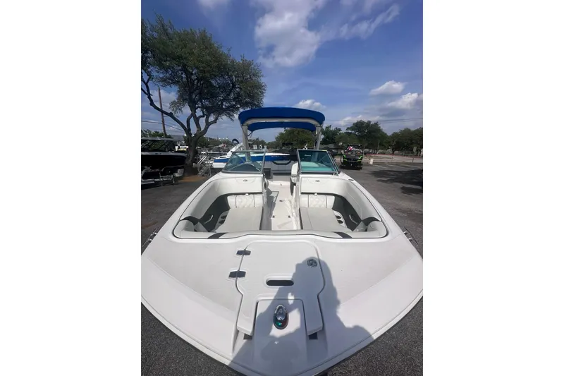 Slide: The Image of 2018 Regal 22 FasDeck boat with open seating, blue canopy, and clear sky background. - 10