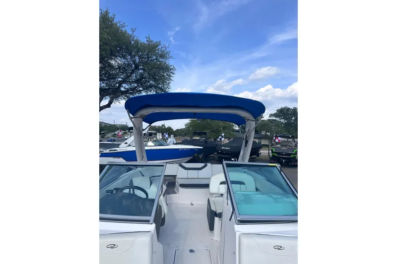 Slide: The Image of 2018 Regal 22 FasDeck boat with blue canopy, parked outdoors under a clear sky. - 34