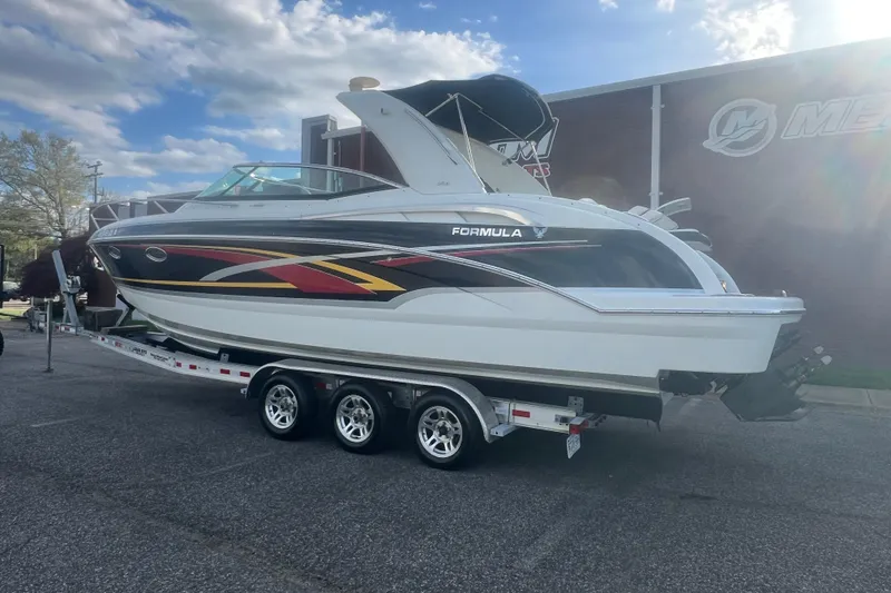 The Image of 2008 Formula 310 Sun Sport boat on trailer, parked outdoors under a partly cloudy sky. - 0