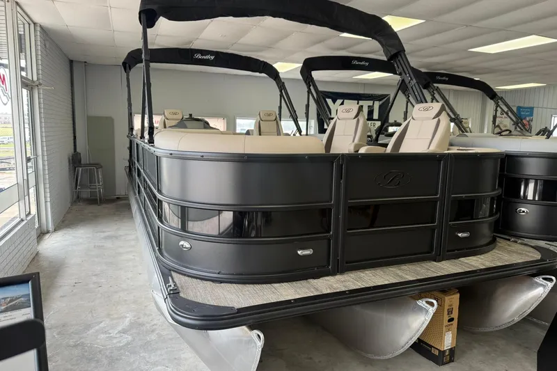 The Image of 2026 Bentley Pontoons Legacy 243 DL Navigator in showroom, featuring sleek black design and comfortable seating. - 0