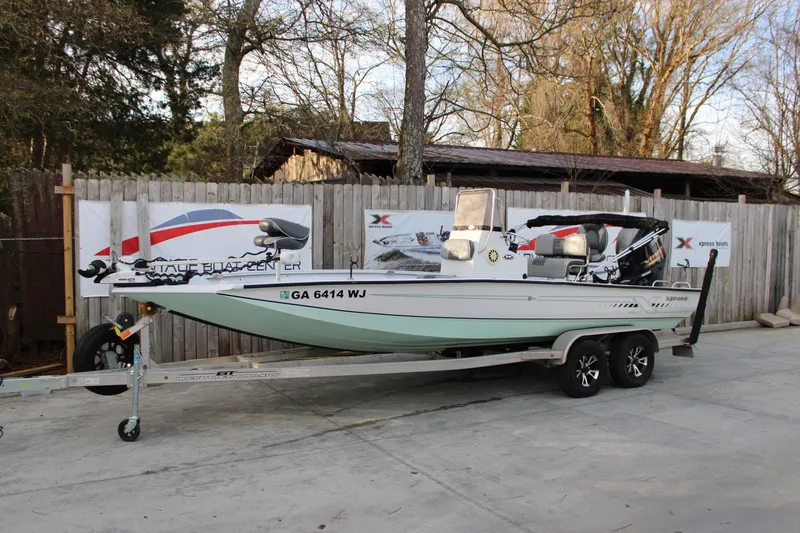 The Image of 2021 Xpress H22B Bay boat on trailer, parked outdoors near wooden fence. - 1