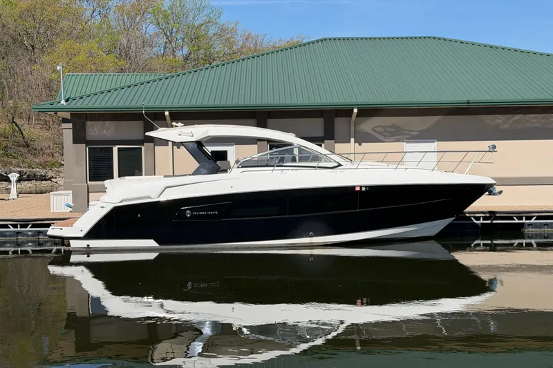 The Image of 2015 Cruisers Yachts 390 Express Coupe docked by a building with green roof. - 0