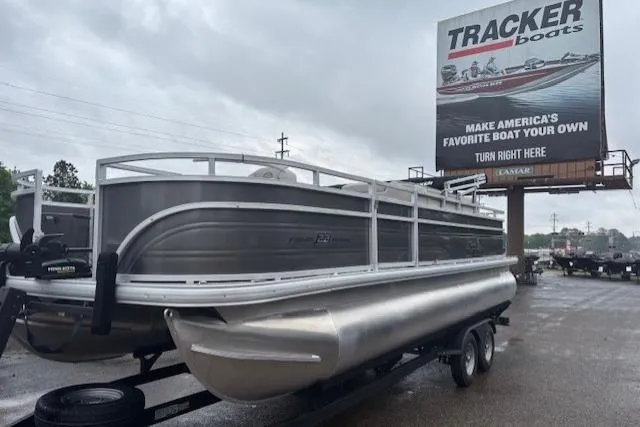 The Image of 2026 Sun Tracker Fishin' Barge 22 DLX pontoon boat on trailer, overcast sky. - 0
