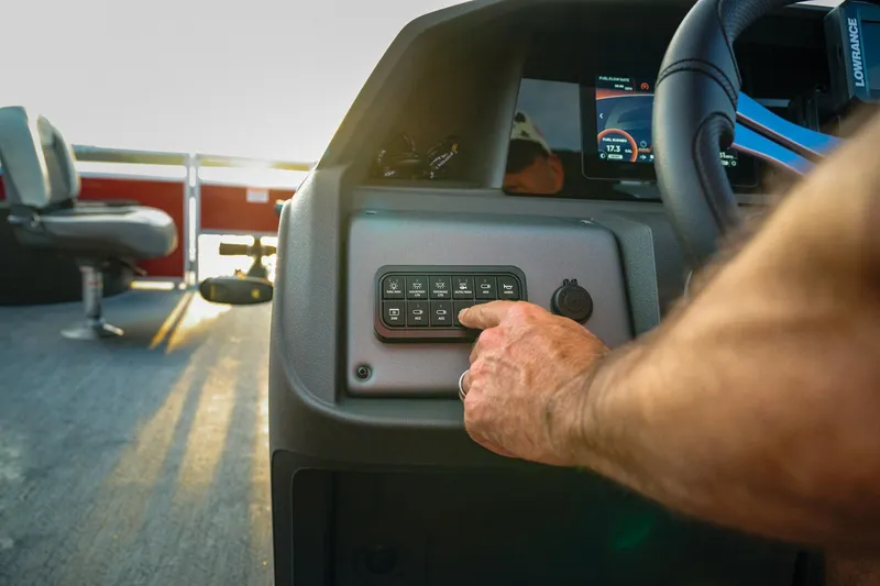 Slide: The Image of Manufacturer Provided Image: Close-up of a hand operating the control panel on a 2026 Sun Tracker Fishin' Barge 22 DLX. - 105