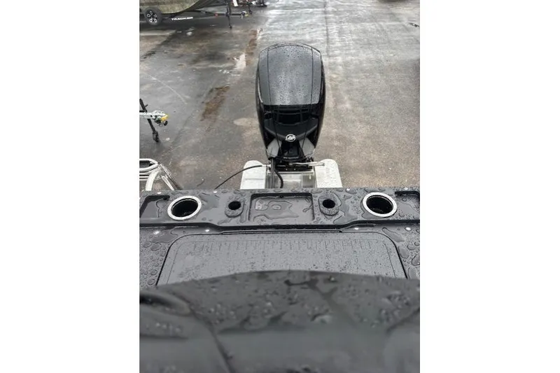 Slide: The Image of 2026 Sun Tracker Fishin' Barge 22 DLX with wet deck and motor, parked on pavement. - 19