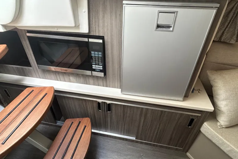 Slide: The Image of 2022 Sea Ray Sundancer 320 Outboard interior with microwave and fridge in cabin. - 23
