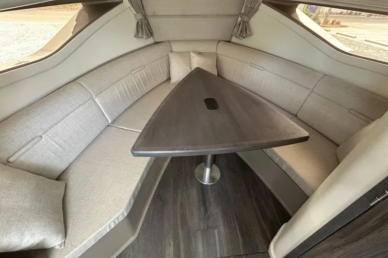 Slide: The Image of Interior of 2022 Sea Ray Sundancer 320 Outboard, featuring a cozy seating area with a triangular table. - 24