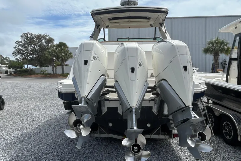 Slide: The Image of 2022 Sea Ray Sundancer 320 Outboard with triple engines, parked on gravel near palm trees. - 4